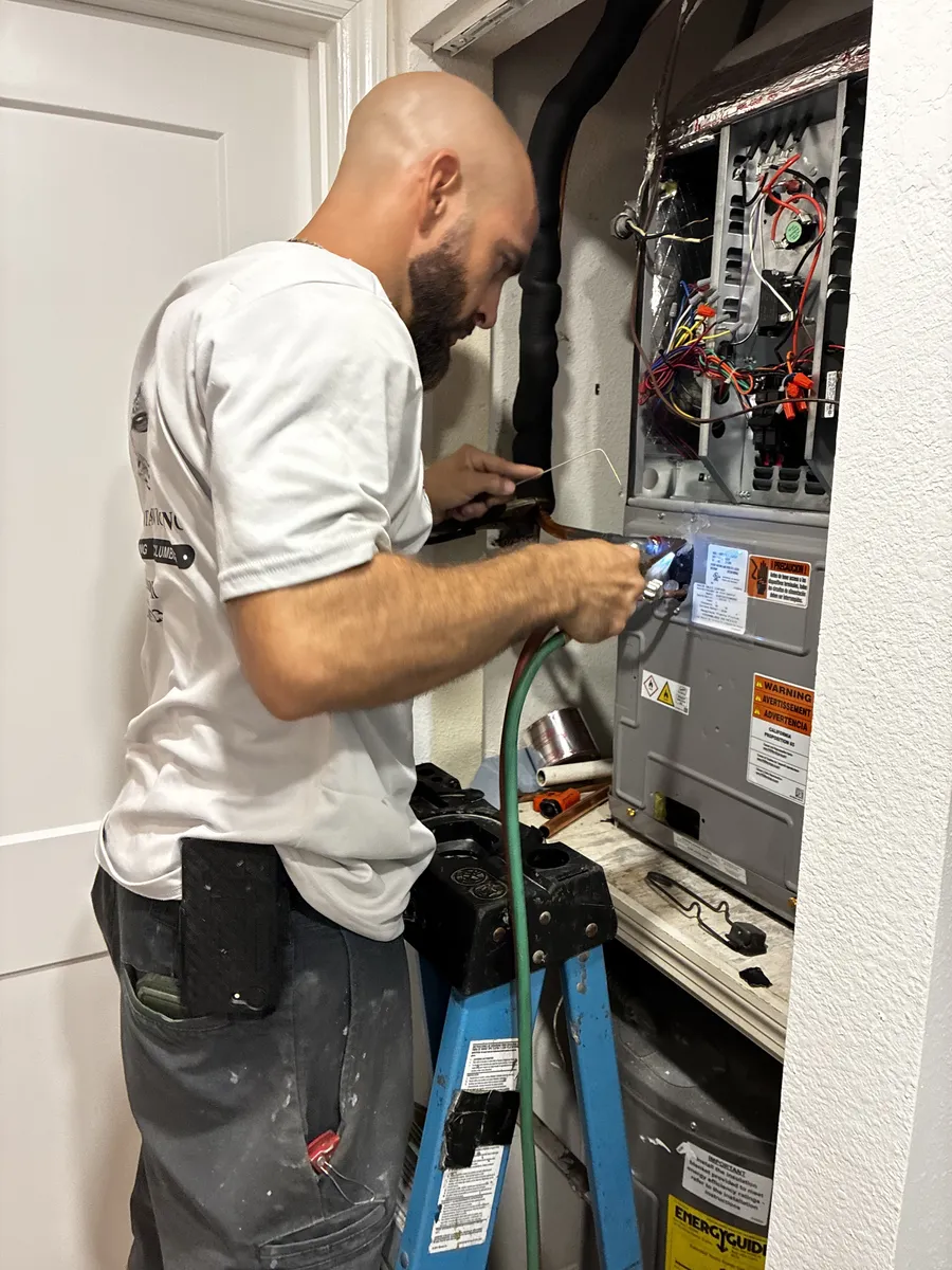 Jackson Total Service technician repairing the control board inside a residential air handler