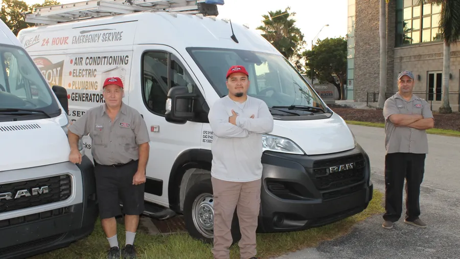 Three Jackson Total Service technicians with their service vans before the morning dispatch