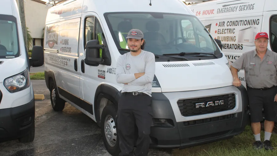 Two Jackson Total Service technicians beside a RAM ProMaster service van