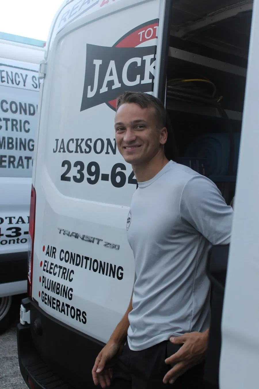 Smiling Jackson Total Service technician at the door of his lettered service van